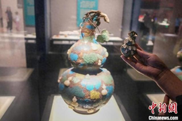 资料图：游客手持“珐琅镶玉葫芦”文创产品与河南博物院馆藏文物对比。 中新社记者 范晓恒 摄