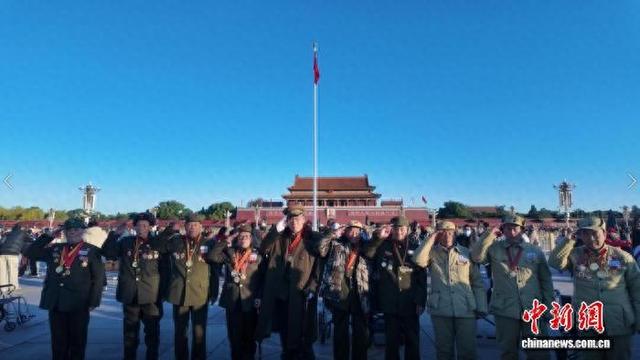 10月26日,10位抗美援朝老兵走进北京天安门广场。图为老兵与五星红旗合影。中新社记者 刘子衿 摄